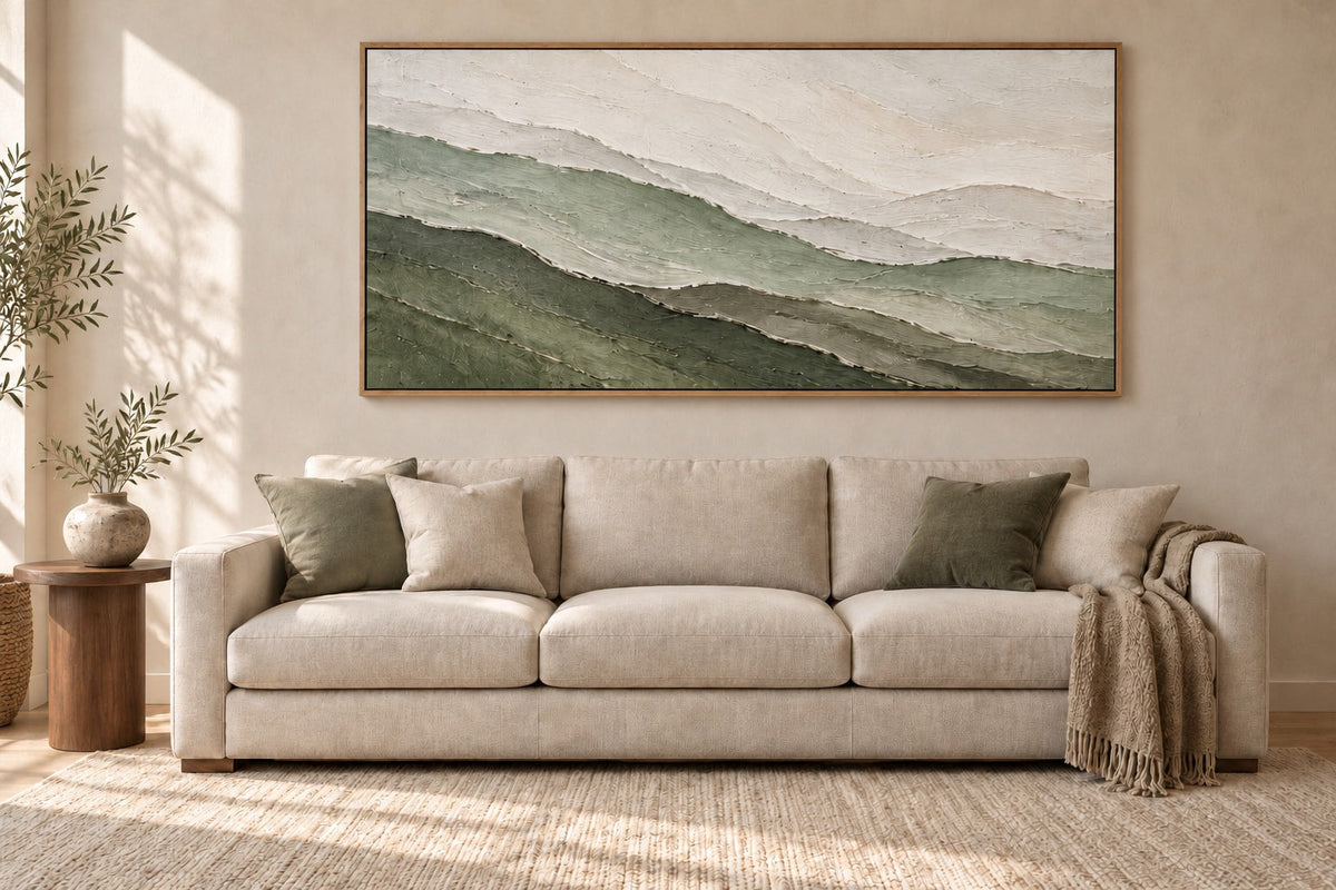 Sage and ivory abstract artwork in an oak frame above a cream sofa in a warm neutral living room.